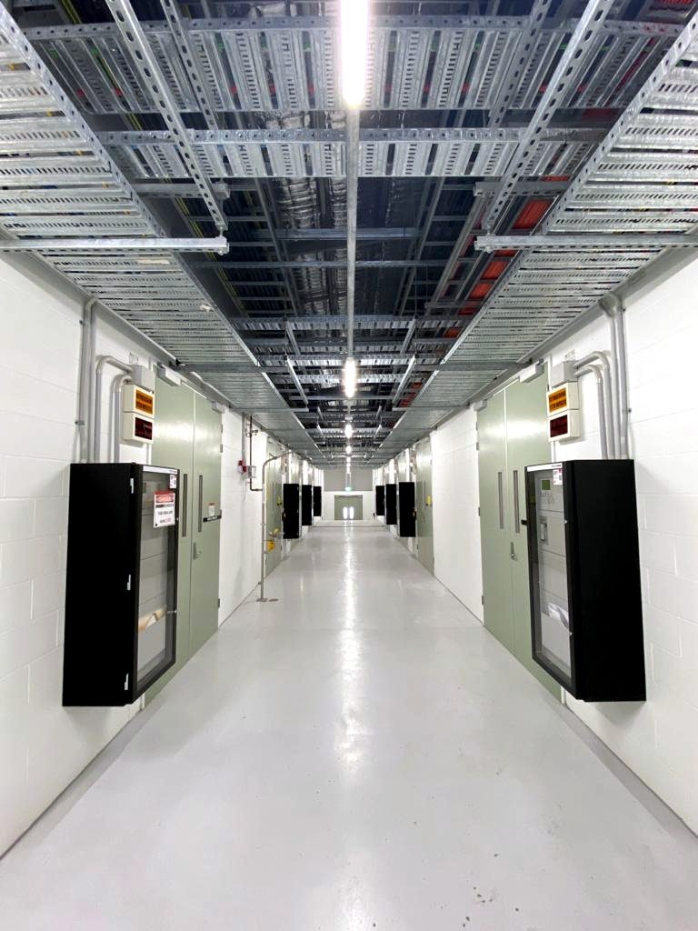 Fire services corridor — wall-mounted detection and EWIS equipment cabinets installed by Interfire Systems